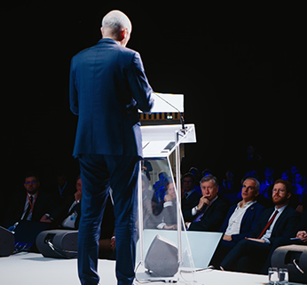 Photo d'un homme parlant à la tribune lors d'un colloque et provenant d'une captation vidéo réalisée par Plan Rapproché