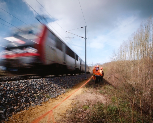 Photo d'un train roulant avec des techniciens de l'ONF en bord de voie