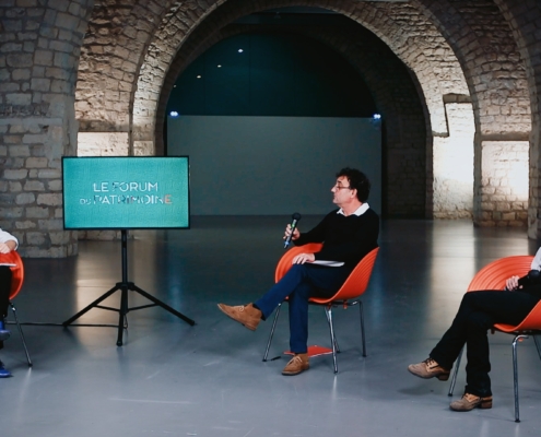 2 invités et une journaliste échangeant sur un plateau TV dans une salle de la cité de l'architecture de Paris