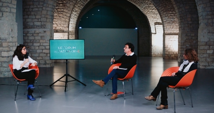 2 invités et une journaliste échangeant sur un plateau TV dans une salle de la cité de l'architecture de Paris