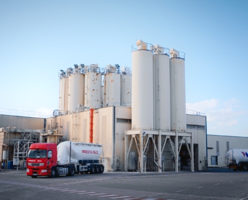 Photo d'une usine dans la Sud de la France avec des silots et des camions.