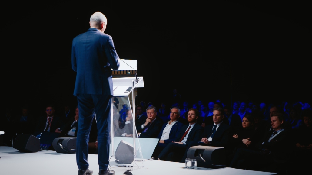 Photo d'un homme parlant à la tribune lors d'un colloque et provenant d'une captation vidéo réalisée par Plan Rapproché