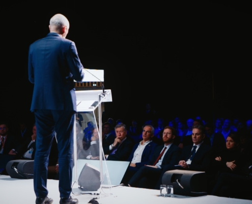 Photo d'un homme parlant à la tribune lors d'un colloque et provenant d'une captation vidéo réalisée par Plan Rapproché