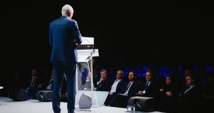 Photo d'un homme parlant à la tribune lors d'un colloque et provenant d'une captation vidéo réalisée par Plan Rapproché