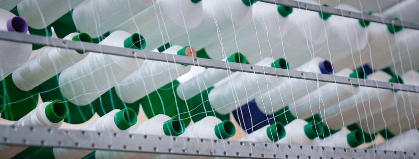 Rouleaux de fils blanc sur un métier à tisser