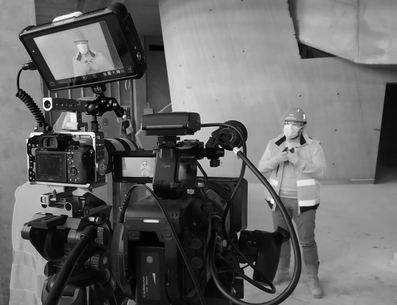 Photo en noir et blanc d'une caméra en train de filmer un homme se faisant interviexer